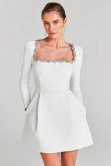 White mini dress with long sleeves and embellished square neckline