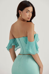 Jadekorsett med volanger på  ärmarna och maxikjol med volanger